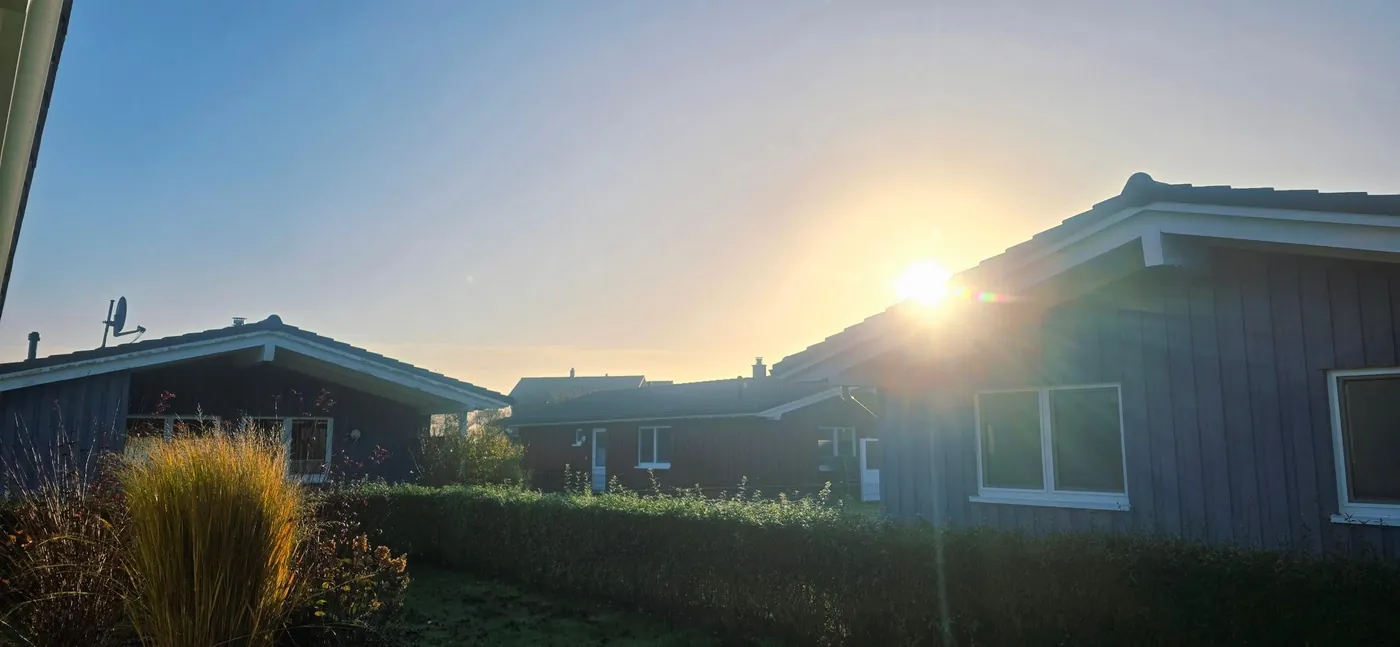 Tiefstehende Novembersonne hinter den Holzhäusern am Möwennest in Dagebüll